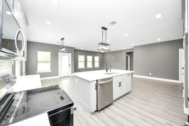 601 Lily St, Waller, TX 77484 - kitchen with appliances with stainless steel finishes, open floor plan, light wood finished floors, white cabinets, and recessed lighting