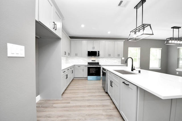 601 Lily St, Waller, TX 77484 - kitchen featuring appliances with stainless steel finishes, backsplash, light countertops, light wood-type flooring, and an island with sink