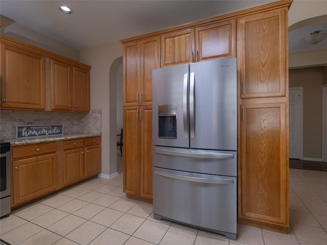 19327 Dickson Park Dr, Spring, TX 77373 - kitchen featuring appliances with stainless steel finishes, arched walkways, light tile patterned floors, backsplash, and light stone counters