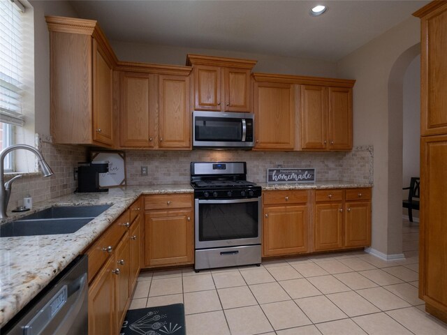 19327 Dickson Park Dr, Spring, TX 77373 - kitchen featuring appliances with stainless steel finishes, backsplash, arched walkways, light tile patterned flooring, and recessed lighting