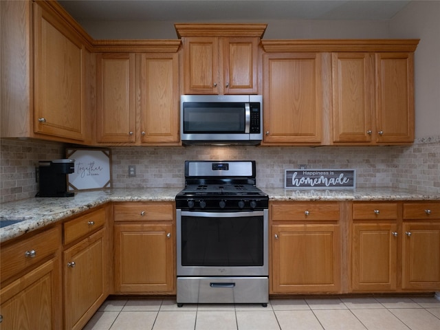 19327 Dickson Park Dr, Spring, TX 77373 - kitchen with appliances with stainless steel finishes, light tile patterned flooring, light stone counters, and brown cabinets