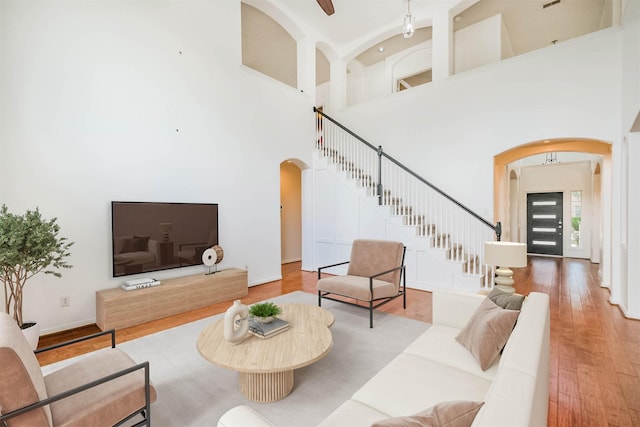 13811 Pepperstone Ln, Houston, TX 77044 - living area featuring arched walkways, stairs, wood finished floors, and a towering ceiling