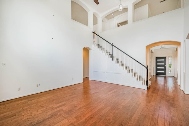 13811 Pepperstone Ln, Houston, TX 77044 - unfurnished living room featuring arched walkways, wood-type flooring, stairs, and a towering ceiling
