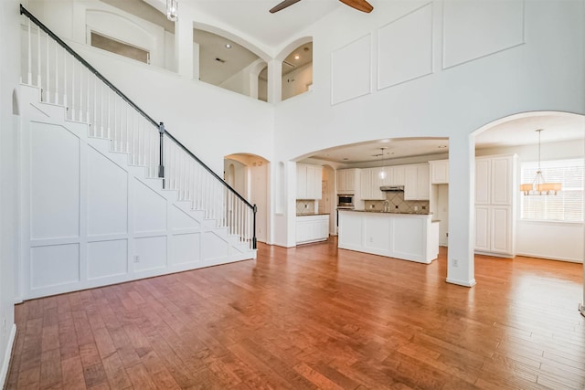 13811 Pepperstone Ln, Houston, TX 77044 - unfurnished living room featuring ceiling fan, a high ceiling, light wood-type flooring, stairs, and a chandelier