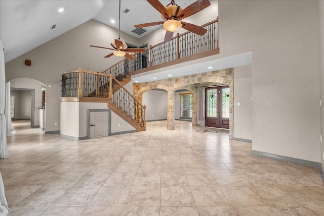 1273 County Road 201a, Angleton, TX 77515 - unfurnished living room with arched walkways, high vaulted ceiling, a ceiling fan, stairs, and french doors