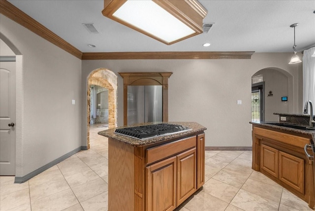 1273 County Road 201a, Angleton, TX 77515 - kitchen with stainless steel appliances, arched walkways, crown molding, brown cabinetry, and a center island