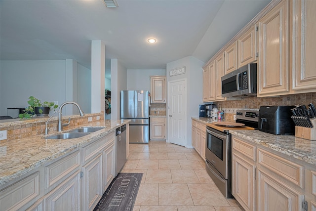12005 Green Falls Dr, Pearland, TX 77584 - kitchen featuring stainless steel appliances, decorative backsplash, light stone counters, light tile patterned floors, and cream cabinets