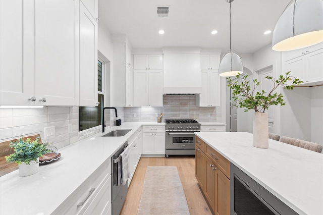 4403 Feagan, Houston, TX 77007 - kitchen featuring appliances with stainless steel finishes, custom range hood, light wood-style floors, light countertops, and backsplash