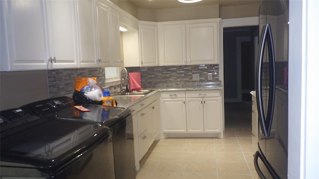 232 Birch St, Lake Jackson, TX 77566 - kitchen with washing machine and dryer, freestanding refrigerator, white cabinets, decorative backsplash, and light tile patterned floors