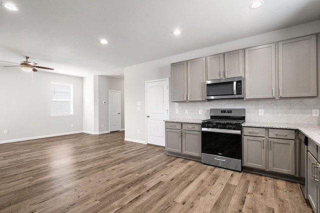 2580 Westslope Dr, Conroe, TX 77384 - kitchen with appliances with stainless steel finishes, gray cabinets, ceiling fan, backsplash, and light wood finished floors