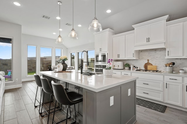 29726 Smoky Ridge Rd, Fulshear, TX 77441 - kitchen with stainless steel microwave, a kitchen island, backsplash, gas cooktop, and light countertops