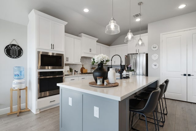 29726 Smoky Ridge Rd, Fulshear, TX 77441 - kitchen featuring appliances with stainless steel finishes, tasteful backsplash, white cabinets, a kitchen breakfast bar, and vaulted ceiling