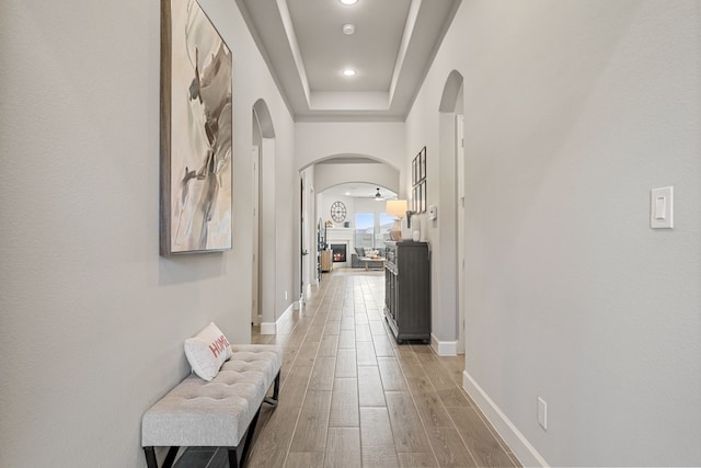 29726 Smoky Ridge Rd, Fulshear, TX 77441 - corridor with arched walkways, light wood-style flooring, recessed lighting, and a raised ceiling