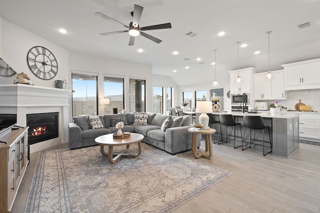 29726 Smoky Ridge Rd, Fulshear, TX 77441 - living area featuring a ceiling fan, light wood-type flooring, a glass covered fireplace, lofted ceiling, and recessed lighting