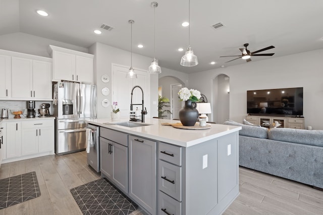 29726 Smoky Ridge Rd, Fulshear, TX 77441 - kitchen with stainless steel appliances, arched walkways, gray cabinetry, light wood-style flooring, and recessed lighting