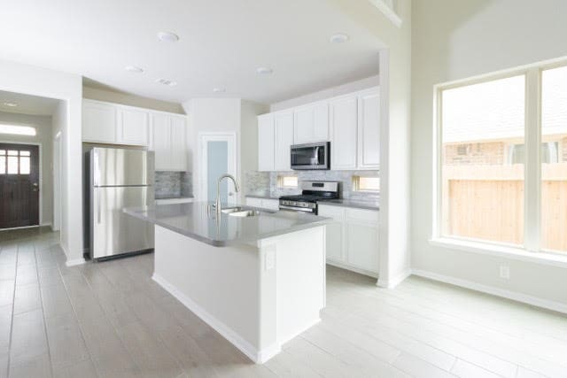 5018 Brewcastle Ln, Katy, TX 77493 - kitchen with stainless steel appliances, backsplash, white cabinets, and a kitchen island with sink