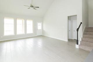 5018 Brewcastle Ln, Katy, TX 77493 - unfurnished living room featuring high vaulted ceiling, stairs, wood finished floors, and a ceiling fan