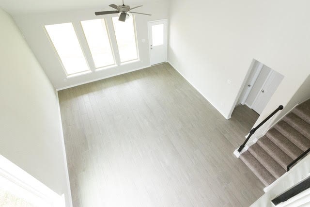 5018 Brewcastle Ln, Katy, TX 77493 - unfurnished living room with wood finished floors, a ceiling fan, and stairs