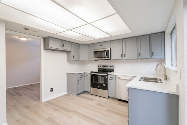 7911 Bova Rd, Houston, TX 77064 - kitchen featuring appliances with stainless steel finishes, gray cabinetry, light wood-style floors, and light countertops