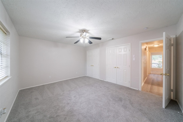 7911 Bova Rd, Houston, TX 77064 - unfurnished bedroom with attic access, two closets, carpet floors, ceiling fan, and a textured ceiling