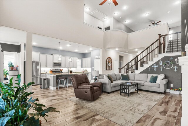 4802 Wagtail Way Ln, League City, TX 77573 - living area with a ceiling fan, light wood-style floors, a towering ceiling, and stairs
