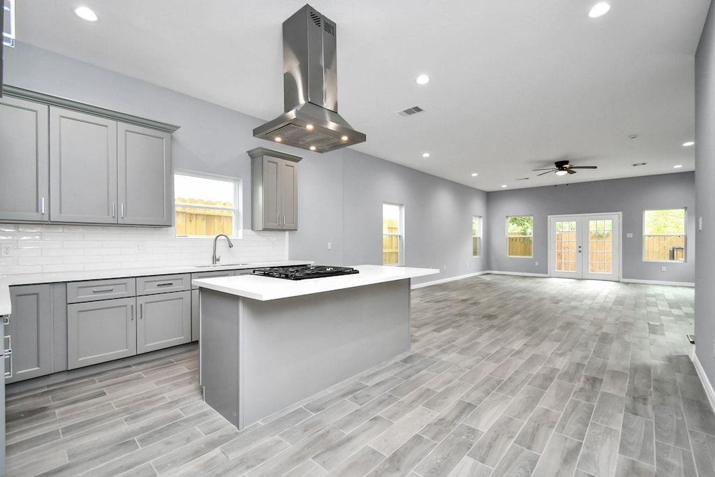 5218 Higgins St, Houston, TX 77033 - kitchen with island exhaust hood, gray cabinetry, black gas stovetop, a ceiling fan, and recessed lighting