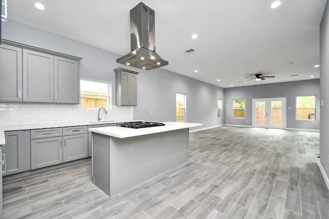 5218 Higgins St, Houston, TX 77033 - kitchen with island exhaust hood, gray cabinetry, black gas stovetop, a ceiling fan, and recessed lighting
