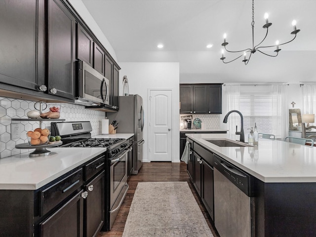 3327 Jane Way, Richmond, TX 77406 - kitchen featuring appliances with stainless steel finishes, dark wood finished floors, a center island with sink, a chandelier, and light countertops