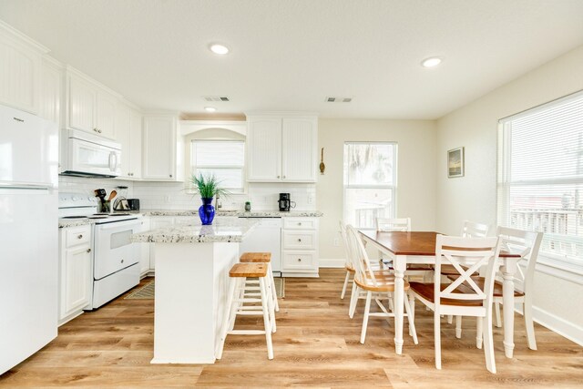 1214 Fort Velasco Dr, Surfside Beach, TX 77541 - kitchen featuring white appliances, a kitchen island, tasteful backsplash, white cabinets, and light wood-style flooring