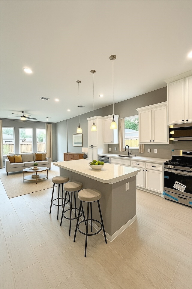 153 Treasure Dr, Houston, TX 77076 - kitchen with stainless steel appliances, a kitchen island, a kitchen bar, white cabinetry, and light countertops