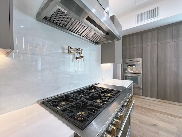 3818 Drake St, Houston, TX 77005 - kitchen with wall chimney range hood, modern cabinets, stainless steel appliances, and light countertops