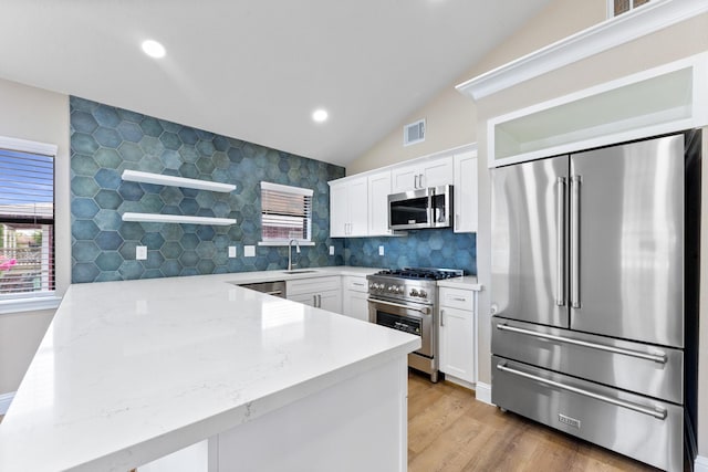 1115 Sunset, Dickinson, TX 77539 - kitchen featuring high end appliances, a peninsula, lofted ceiling, open shelves, and white cabinetry