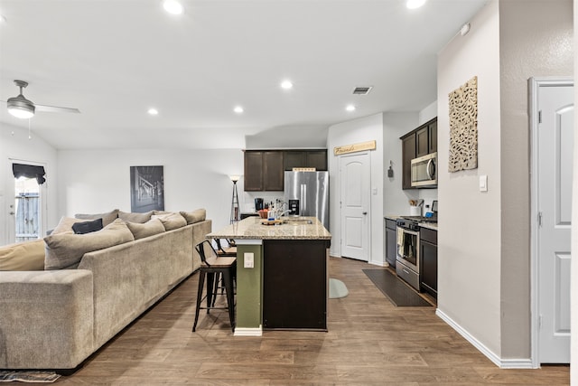 20214 Portbec Dr, New Caney, TX 77357 - kitchen with appliances with stainless steel finishes, open floor plan, a breakfast bar area, ceiling fan, and dark wood finished floors