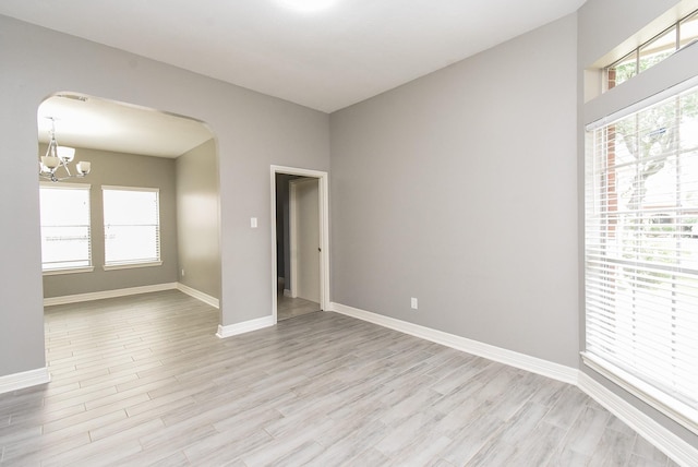 4706 Torrington Ct, Sugar Land, TX 77479 - empty room featuring arched walkways, a chandelier, light wood-type flooring, and plenty of natural light