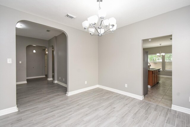 4706 Torrington Ct, Sugar Land, TX 77479 - empty room with a chandelier, arched walkways, and light wood finished floors
