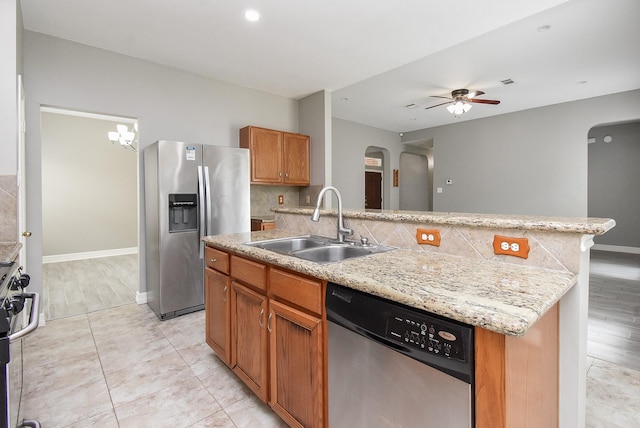4706 Torrington Ct, Sugar Land, TX 77479 - kitchen featuring appliances with stainless steel finishes, arched walkways, ceiling fan, brown cabinets, and backsplash