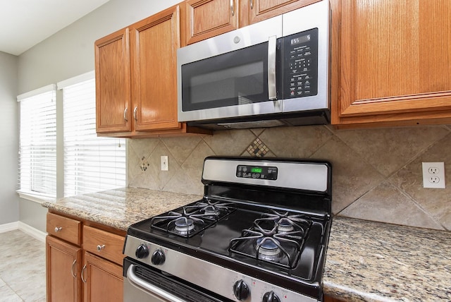 4706 Torrington Ct, Sugar Land, TX 77479 - kitchen with appliances with stainless steel finishes, tasteful backsplash, brown cabinets, and light stone counters