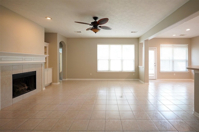 105 N Hollylaurel Cir, The Woodlands, TX 77382 - unfurnished living room featuring a tile fireplace, ceiling fan, light tile patterned floors, arched walkways, and recessed lighting