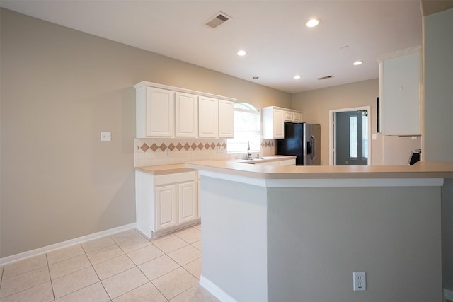 105 N Hollylaurel Cir, The Woodlands, TX 77382 - kitchen featuring stainless steel fridge with ice dispenser, decorative backsplash, white cabinetry, light tile patterned floors, and light countertops
