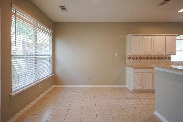105 N Hollylaurel Cir, The Woodlands, TX 77382 - kitchen featuring decorative backsplash, light countertops, white cabinets, and light tile patterned flooring