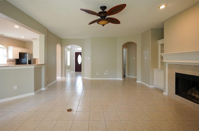 105 N Hollylaurel Cir, The Woodlands, TX 77382 - unfurnished living room featuring ceiling fan, light tile patterned flooring, a tiled fireplace, arched walkways, and recessed lighting