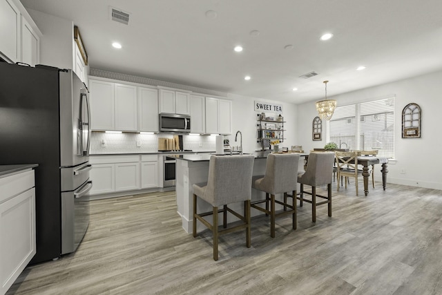 10009 Gray Jay Ct, Conroe, TX 77384 - kitchen with appliances with stainless steel finishes, recessed lighting, tasteful backsplash, a kitchen breakfast bar, and white cabinets