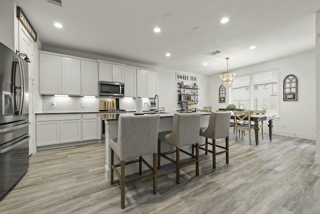 10009 Gray Jay Ct, Conroe, TX 77384 - kitchen with stainless steel appliances, backsplash, recessed lighting, light wood-style flooring, and a kitchen breakfast bar