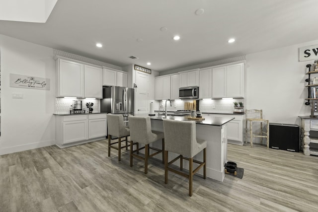 10009 Gray Jay Ct, Conroe, TX 77384 - kitchen with stainless steel microwave, tasteful backsplash, a breakfast bar, recessed lighting, and dark countertops