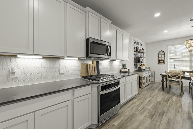 10009 Gray Jay Ct, Conroe, TX 77384 - kitchen with appliances with stainless steel finishes, dark countertops, recessed lighting, light wood finished floors, and tasteful backsplash