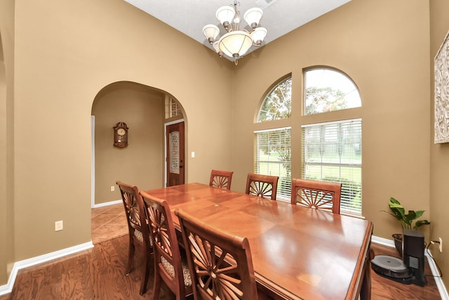 5874 Natchez Trce, Baytown, TX 77523 - dining space featuring arched walkways, a chandelier, wood finished floors, and a high ceiling
