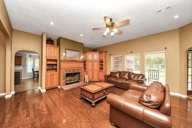 5874 Natchez Trce, Baytown, TX 77523 - living room with arched walkways, ceiling fan, a brick fireplace, dark wood finished floors, and recessed lighting