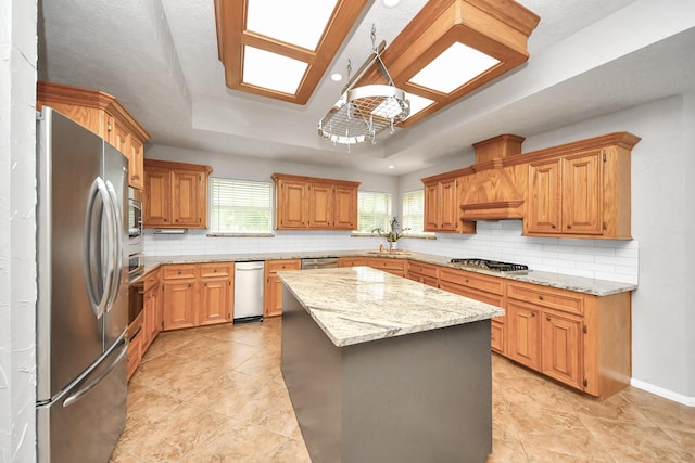 5874 Natchez Trce, Baytown, TX 77523 - kitchen with stainless steel appliances, a raised ceiling, backsplash, a center island, and light stone counters