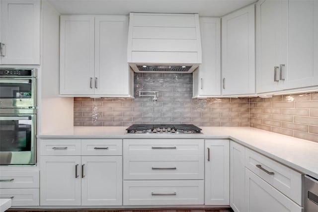 7710 Meadowvale Dr, Houston, TX 77063 - kitchen with custom range hood, appliances with stainless steel finishes, light countertops, and white cabinets