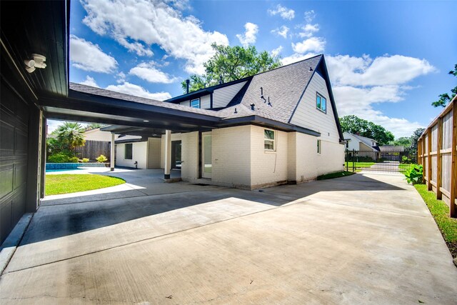 7710 Meadowvale Dr, Houston, TX 77063 - view of home's exterior featuring a patio, brick siding, concrete driveway, and a shingled roof